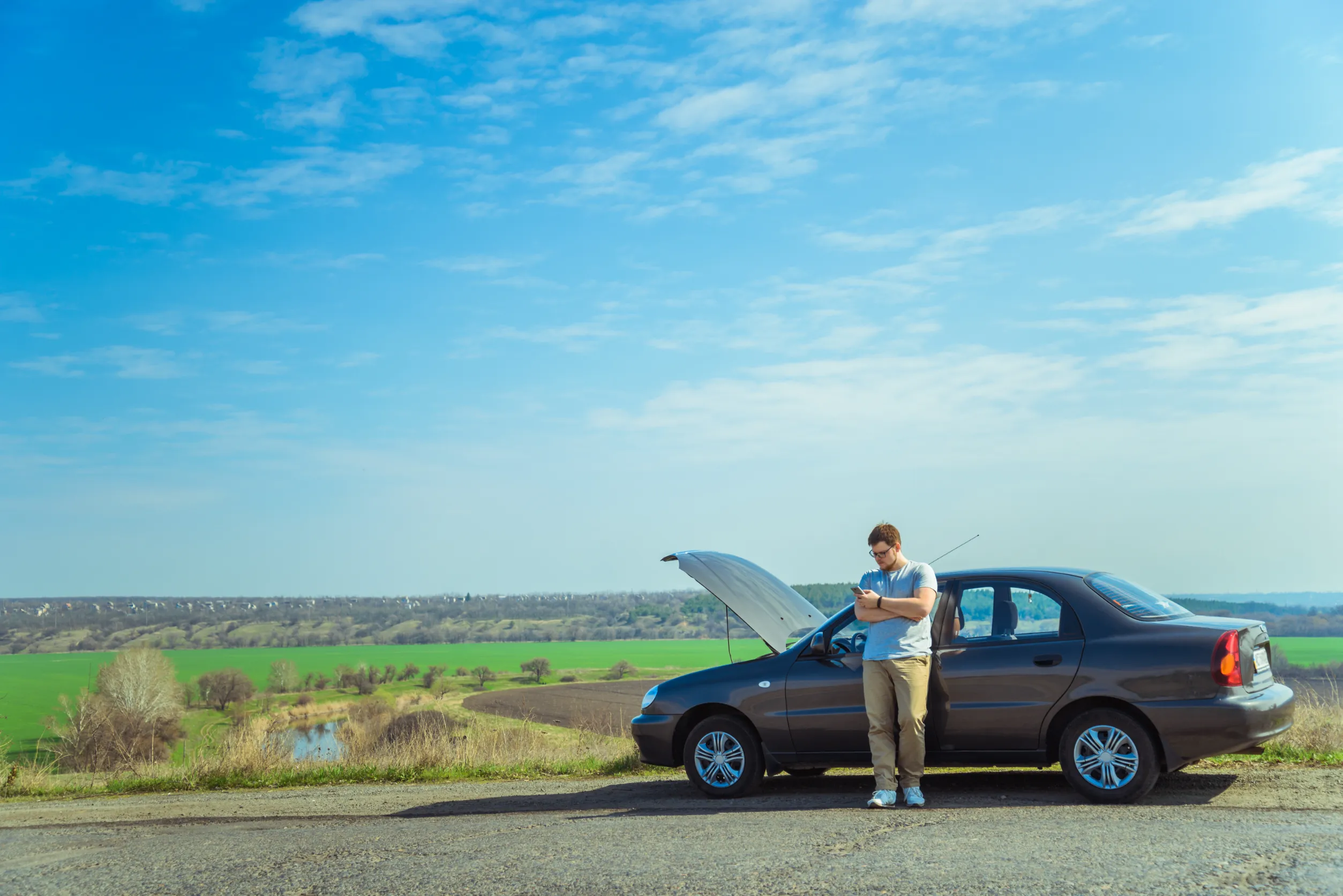 Man waiting on highway beside broken down car with wrong fuel issue in Sydney